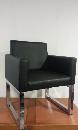 Armchair with metal chassis and covered in black imitation leather
